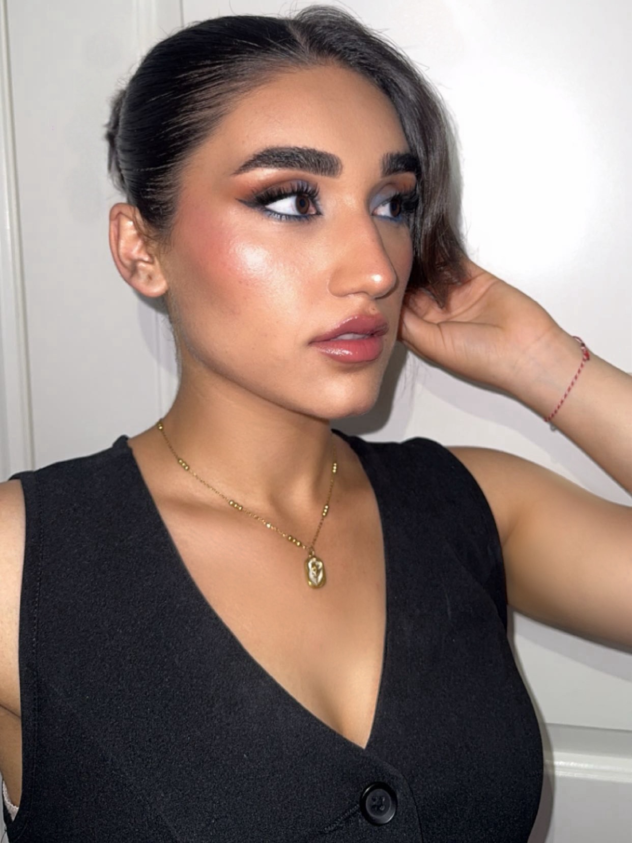 Kocer’s own look: a warm sculpted face, winged liner and glossy lips, in a black top